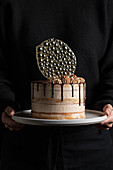 Unrecognizable person holding a festive cake with chocolate filling and frosting and silver isomalt decoration