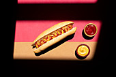 Frankfurt hot dog with mustard and ketchup served on small bowls on colorful background