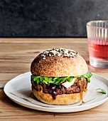 Delicious homemade camembert burger with berry jam placed on wooden table