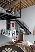 Essbereich mit Klassikerstühlen vor Treppenaufgang, im Vordergrund Designerstühle in Loft-Wohnung
