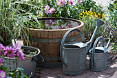 Wooden barrel and zinc tub with water, blooming saintly herb and dahlia