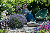 Woman relaxes in the garden next to lavender and roses