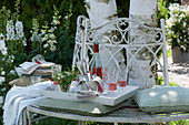 Weißes Tablett mit Strauß aus Walderdbeeren, Besteck und Servietten, Rosato in Flasche und Gläsern auf Baumbank