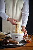 Man in an apron kneading yeast dough in a bowl