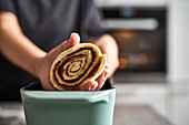Preparing cinnamon roll cake: placing a rolled cake in a baking pan