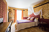Doppelbett mit Baldachin im Schlafzimmer mit Natursteinwänden