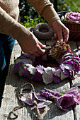 Woman creating wreath of ornamental cabbage leaves and sedum