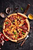 Pizza mit Mozzarella, Parmaschinken, Oliven und Basilikum