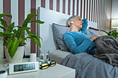 Senior woman sleeping with ear plugs