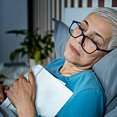 Senior woman falling asleep reading