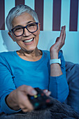 Smiling senior woman watching television