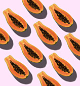 Papaya halves on a pink background