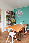 Dining table with solid wooden top next to turquoise wall and shelving