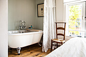 Vintage bathtub behind curtain in bedroom