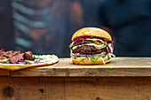 A hamburger and a tarte flambée on wooden counter