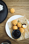Delicious potato balls with cheese filling served with sauce on plate on wooden table