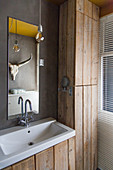 Sink next to rustic fitted cupboard made from reclaimed wooden boards