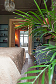 Potted palm and bed in bedroom with open door