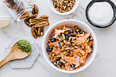 Bowl with slices of carrot in yogurt dressing with pecan nuts and prunes on marble table