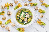 Exotic soup with mushroom and cucumber and flowers of zucchini