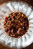 Top view of aromatic dried fruits and herbs placed on bottom of glass cup