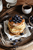 Ein Stapel Pancakes mit Blaubeeren auf Holztablett