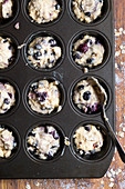 Mixed berry and oat muffin batter spooned into a patty cake pan