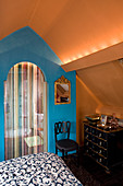 Kommode vor blauer Wand und Türvorhang im Schlafzimmer