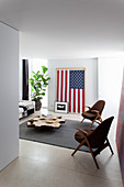 Stühle um Couchtisch aus Baumscheibe vor US-Flagge an der Wand