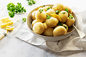 Whole steamed potatoes with butter and parsley in a ceramic bowl