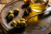 Olivenölkaraffe auf Holzteller mit schwarzen und grünen Oliven