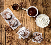 Frisch gebackene runde Brownies, Schokoladensauce und Sahne auf Holztisch