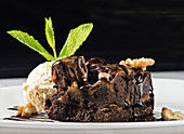 Chocolate brownie cake with milk ice cream and crushed nuts on plate