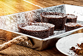 Rustic metal tray with chocolate coulants sprinkled lightly with icing sugar