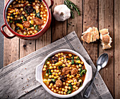 Chickpea stew with chard and aromatic chorizo on timber background