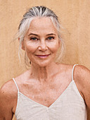 A grey-haired woman wearing a spaghetti-strap top