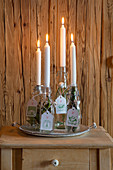 Advent arrangement of four white tapered candles in swing-top bottles