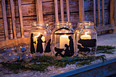 White candles in mason jars painted with festive silhouettes