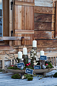 Advent arrangement of white candles on logs with numbered signs
