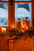 Arrangement of cinnamon-stick angels and candles in rustic window