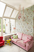 Pink sofa against wallpaper with bird motif in girl's bedroom
