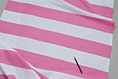 Pink-and-white striped cloth and darning needle