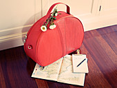 A red handbag with flowers, a note boot and a map