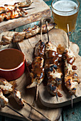 Pork skewers served with BBQ sauce and beer