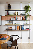 An open bookshelf with a round wooden table and a designer chair in front of it