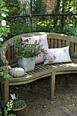 Cushions, potted petunias and ornamental squash on garden bench