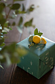 Wrapped gift decorated with eucalyptus sprig, yarrow and yellow felt ball