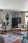 A bedroom corner with a black dresser, a decorative mirror and a 1930s Art Deco-style chinoiserie wallpaper