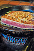 A tuna steak being fried in a pan