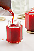 Filling strawberry jam jars
